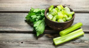 Pieces of celery in a bowl. On wooden background