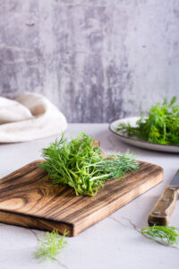 A bunch of fresh dill on a cutting board on the table. Organic seasoning. Vertical view